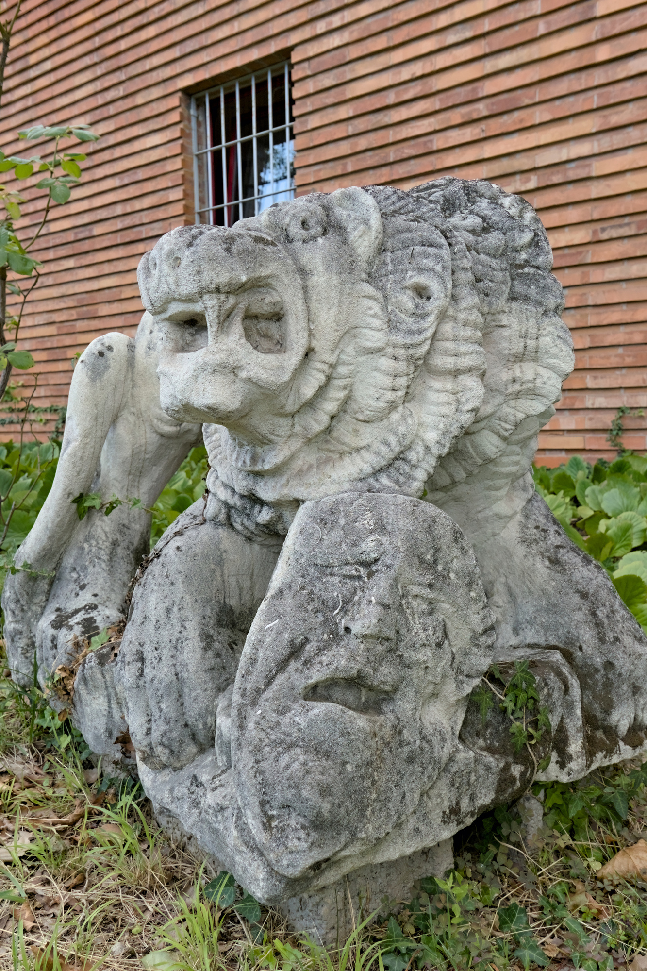 Amleto Sartori, leone che ghermisce una maschera di teatro, 1940, originariamente sulle torri di ingresso del Teatro dei Diecimila, ora nel cortile del Centro Sportivo Universitario di Padova (C.U.S.), ex Gruppo Rionale Fascista Bonservizi (Quirino De Giorgio, 1937-38), via Giordano Bruno 27, Padova