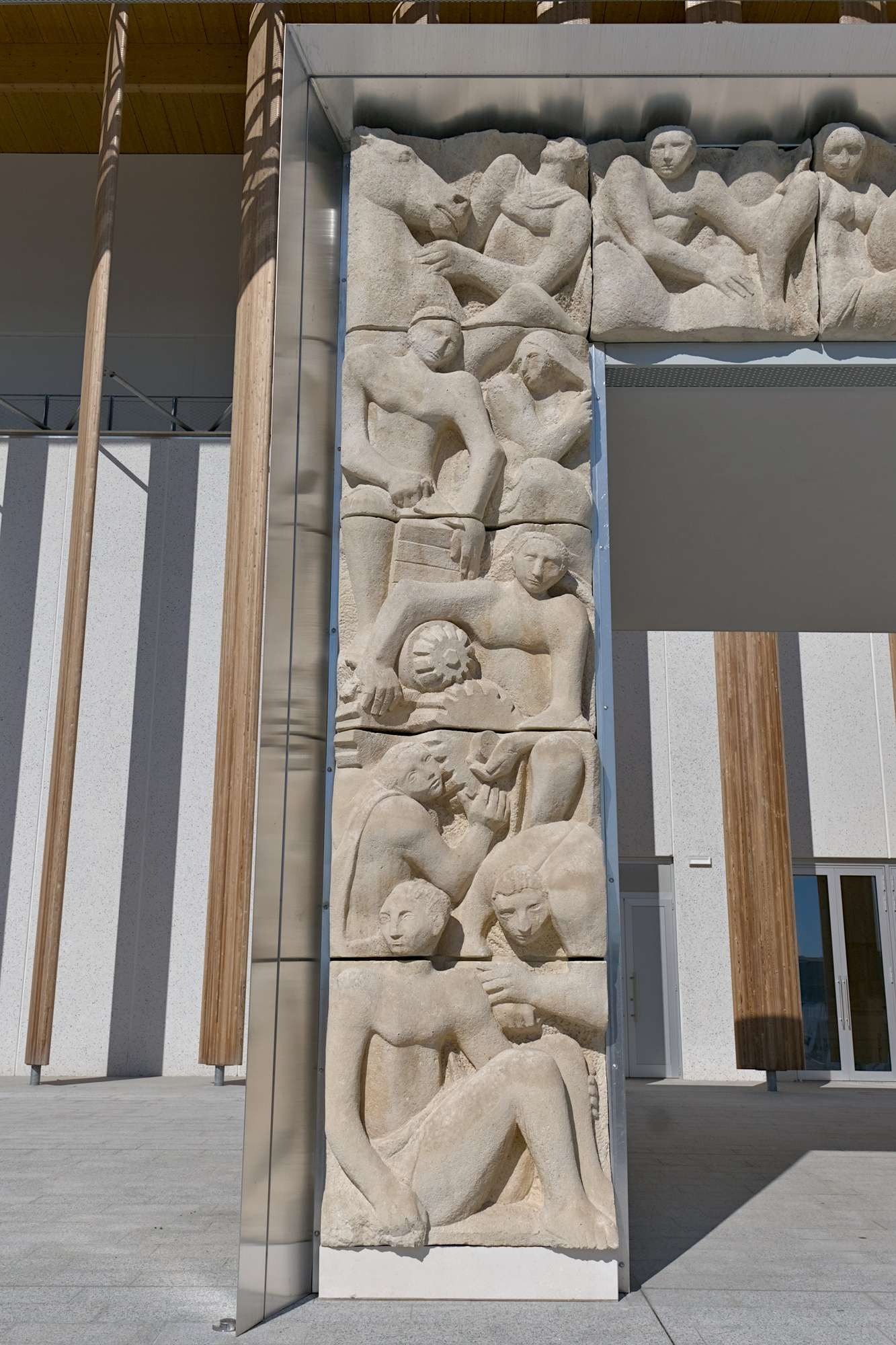 Luigi Strazzabosco, parte sinistra del rilievo in pietra *Arti e mestieri*, portale d’ingresso al Palazzo delle Nazioni alla Fiera di Padova, 1951-52, via Niccolò Tommaseo 59, Padova